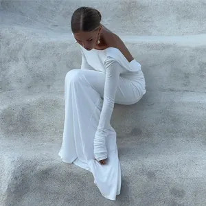 Elegant white long sleeve backless maxi dress shown in a side sitting pose.