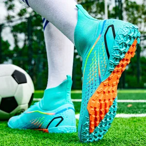 Detailansicht türkisfarbener Fußballschuhe mit hohen Socken und orangefarbenen Stollen.