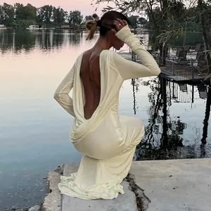 Detail view of sexy backless cream long-sleeve maxi dress in a lakeside setting