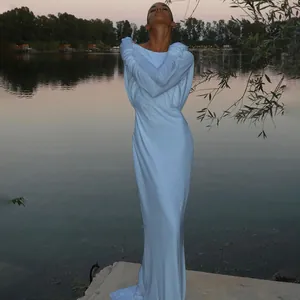 Full view of elegant backless long sleeve maxi dress in a scenic outdoor lakeside setting.