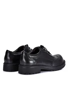 Vista posteriore di scarpe derby in pelle nera con suola spessa e dettagli curati.