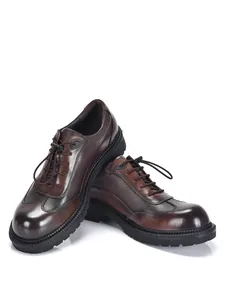 Dettaglio di scarpe derby in pelle marrone con suola spessa e grana naturale.