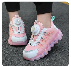 Close-up of pink kids' sneakers with a rotating knob lacing system and chunky sole.