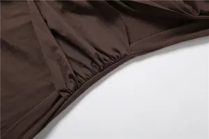 Detailed macro shot of gathered waist pleats on elegant dark brown long sleeve dress