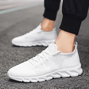 Primo piano di sneakers bianche in mesh fly-knit traspiranti indossate ai piedi dai modelli.