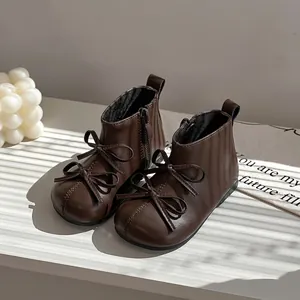 Dark brown baby boots with bow decoration and side zipper on a white surface