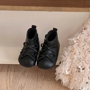 Close-up detail of black toddler boots featuring an elegant double bow design on front