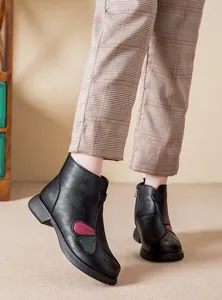 Dettaglio di stivaletti in pelle nera con elegante motivo a farfalla per donna.
