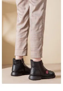 Dettaglio di stivaletti invernali neri da donna con toppe decorative e zip laterale