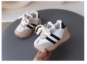 Close-up detail of children's retro sneakers featuring cream leather and black stripes
