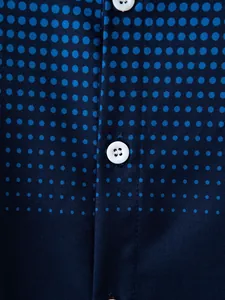 Dettaglio macro del motivo a pois blu e bottone bianco su camicia casual blu scuro