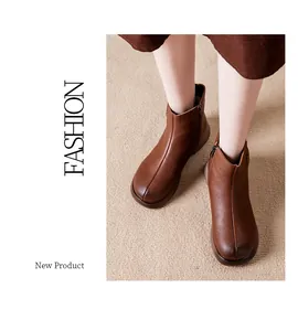 Close-up view of warm brown leather ankle boots with zipper detail on a model