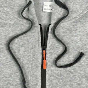 Detail view of gray zip-up sweatshirt showing high-quality zipper and orange puller