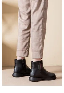 Side view of black leather ankle boots with warm plush lining and decorative round patch