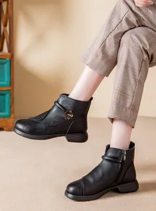 Close-up of black winter ankle boots for women featuring flower detail and side zipper