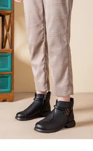 Close-up detail of black leather ankle boots with decorative flower accent for women