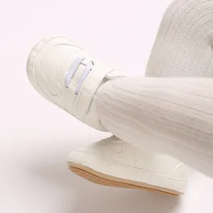 Dettaglio scarpe da camminata per neonati con suola morbida bianca e lacci elastici