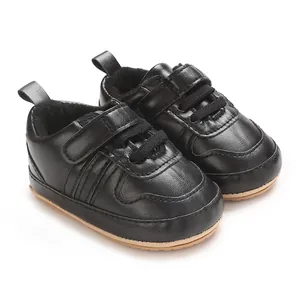 Primo piano di sneakers nere per neonati con suole morbide e cinturini a strappo regolabili.