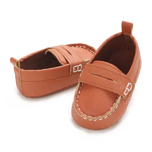 Detailed macro shot of brown faux leather baby loafers with soft sole and white stitching