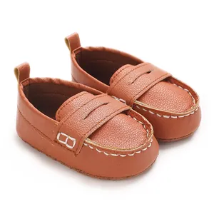 Close-up detail showing the texture and stitching of brown faux leather baby loafers.