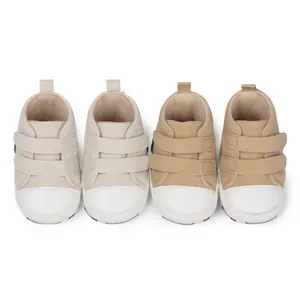 Primer plano de zapatos de aprendizaje para bebés con suela blanda en beige y caqui.