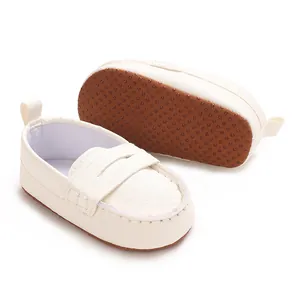 Close-up detail of white soft-sole baby loafers featuring a non-slip brown rubber dotted sole