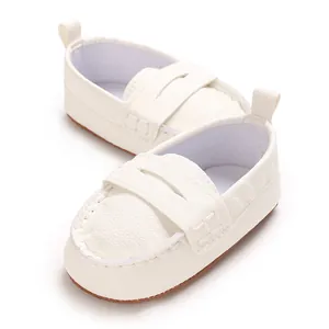 Macro view of elegant white faux leather baby loafers with soft non-slip soles for infants.