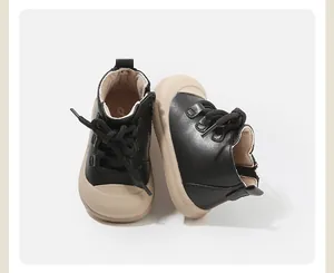 Detailansicht von Kleinkinder-Laufschuhen mit schwarzem Leder und beigen Gummisohlen.