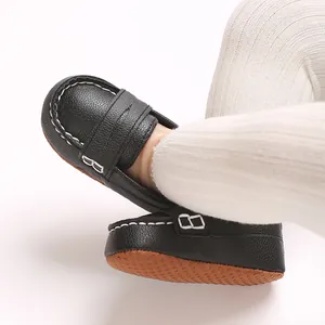 Close-up of black soft-sole baby loafers with white stitching and non-slip bottom.