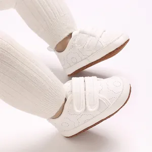 Nahaufnahme von weißen, weichen Baby-Lernlaufschuhen aus Baumwolle mit Klettverschluss