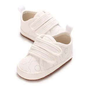 Nahaufnahme von weißen, weichen Baby-Lernlaufschuhen aus Baumwolle mit doppeltem Klettverschluss
