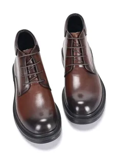 Detailaufnahme der glänzenden braunen Lederstruktur und der Nähte dieser Herrenstiefel.