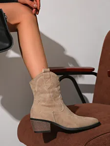 Close-up of beige suede Western cowboy boot with delicate embroidery and pointed toe