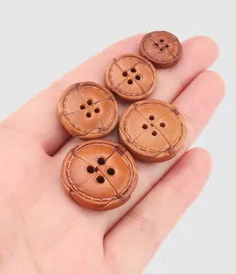 Detailed macro view of premium brown leather decorative buttons in various sizes held in a hand