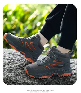Children's high-top outdoor hiking shoes in grey and orange worn on a rocky surface
