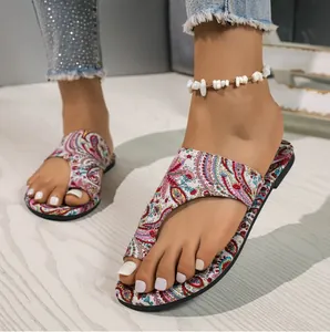 Detailed view of floral paisley print flat toe-loop sandals for summer beach wear.