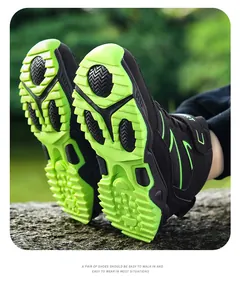 Detailed view of rugged neon green outsole on boys' black high-top hiking shoes