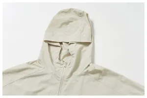 Close-up detail of the windproof hood and front zipper on a beige outdoor jacket