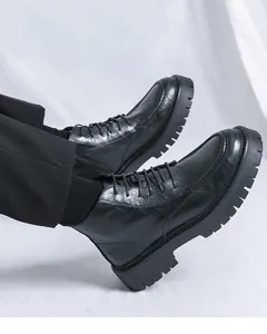 Detailed macro shot of men's chunky black platform Martin boots with textured leather finish