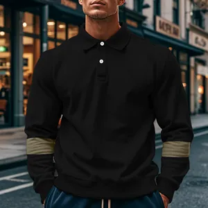 Detail van een zwart poloshirt met lange mouwen en kaki contrastpanelen op de mouwen.