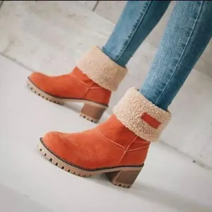 Close-up van oranje suède halfhoge laarzen met blokhak en een warme schapenvacht kraag.