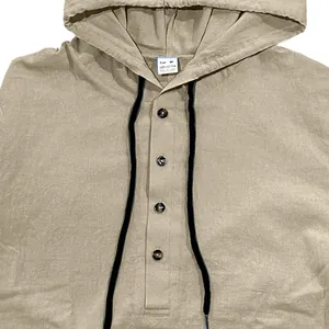 Close-up of men's tan cotton hooded shirt with black drawstrings and button placket detail