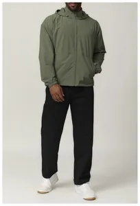 Man wearing an olive green hooded windbreaker with black pants and white sneakers