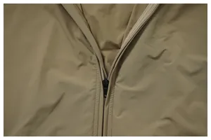 Close-up detail of khaki water-repellent jacket showing zipper and fabric texture