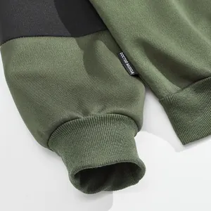 Detailopname van de geribbelde manchet en het Doctor Muscle-label op een groene sweatshirt