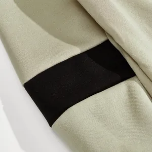 Detailopname van zware gebreide stof met zwart-beige kleurblokontwerp op een polo sweatshirt.