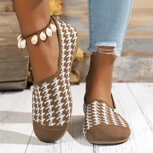 Detalle de mocasines para mujer con estampado de pata de gallo y botón de perla decorativo.