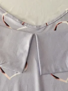 Detail view of purple heart print T-shirt showing neckline and shoulder pleats