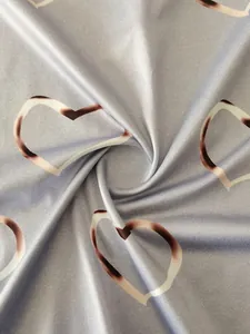 Close-up of soft grey-blue fabric featuring elegant heart-shaped prints with subtle shading.