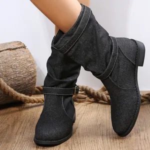 Stylische schwarze Jeans-Stiefeletten mit Schnallendetail auf einem rustikalen Holzhintergrund